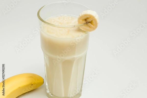 Fototapeta Glass of milk with bananas in it. Woman is drinking banana on gray background. Woman is drinking fruit milk from banana on gray background. A woman is drinking milk from a banana and a lifestyle.