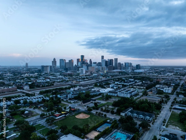 Obraz Aerial view capturing Houston's skyline at dawn with cold tones. Skyscrapers rising above a misty cityscape, highways, and neighborhoods set against a dramatic cloudy backdrop