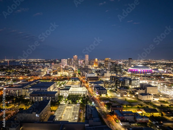 Obraz Glowing New Orleans city skyline at dusk with illuminated buildings, busy streets, and the Caesars Superdome, creating a captivating urban night view