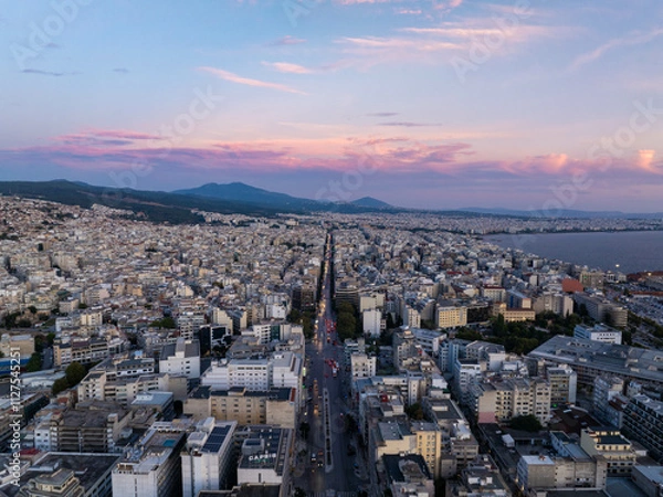Obraz Aerial shot of Thessaloniki city center at sunset, with vibrant clouds above busy streets and tall buildings, overlooking the Thermaic Gulf in Greece