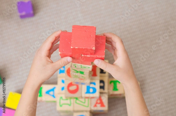 Fototapeta Red cross of cubes by kid hands
