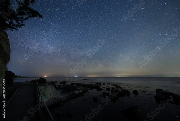 Fototapeta 海沿いの遊歩道から見る水面の星と能登半島の星空