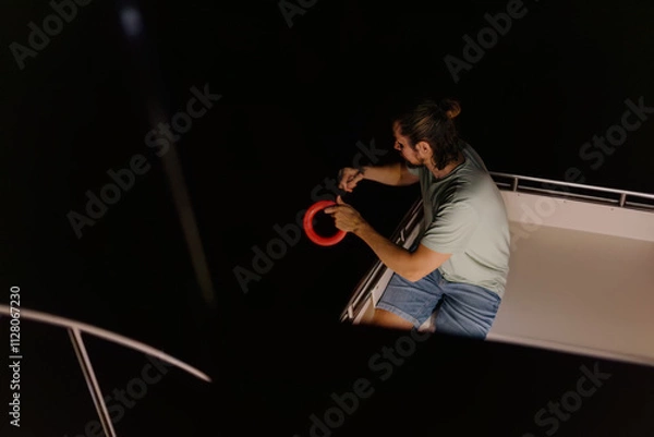 Fototapeta Adult caucasian male fishing on boat at night