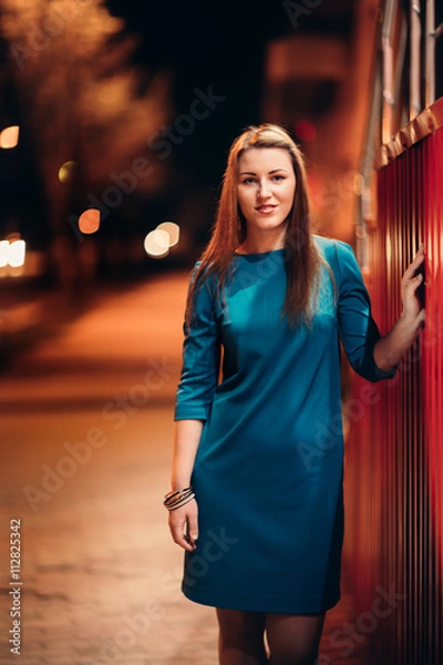 Fototapeta beautiful girl in a blue dress against the backdrop of the city at night