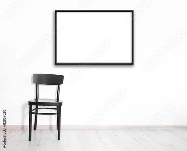 Fototapeta Black chair and empty picture frame on wall background