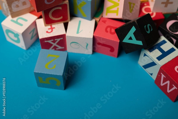 Fototapeta A colourful jumble of alphabet blocks scattered on a bright blue background