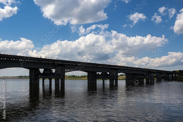 Fototapeta A bridge over a river. A bridge with clouds and a river in the sky. Blue bridge in the nature with blue sky. Blue sky and clouds over the lifestyle bridge in nature.