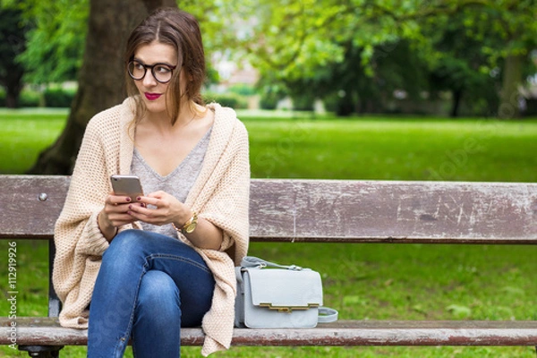Obraz Thoughtful student girl holding phone in the park