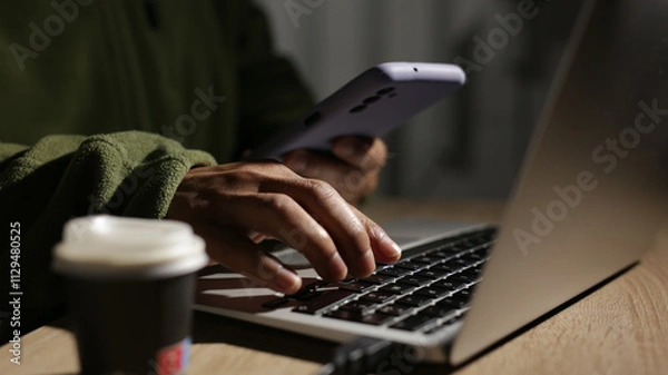 Fototapeta Programmer is working on laptop and using smartphone at night