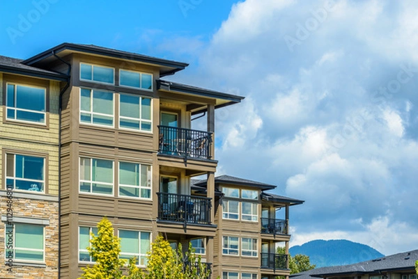 Fototapeta Top of grey stucco luxury house with shingle roof, red and yellow trees and nice windows in Summer in Vancouver, Canada, North America. Day time on June 2024.
