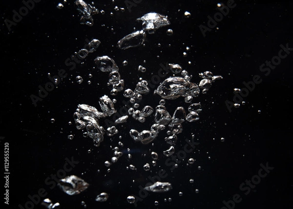 Fototapeta Bubbles and silver particles floating in dark water creating a mesmerizing effect