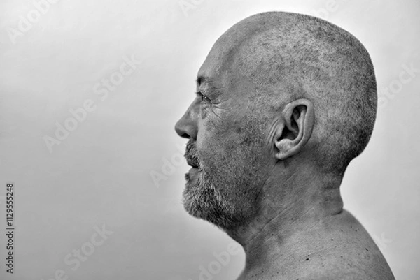 Fototapeta Profile of an adult man with a shaved head and a hopeful gaze