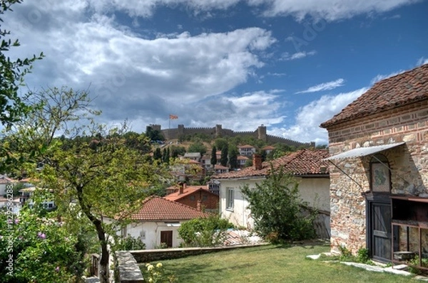 Fototapeta Historical part of old town Ohrid is located next to the lake and spread all over the hill with fortress of king Samuel at the top.  Dramatic clouds in the sky.