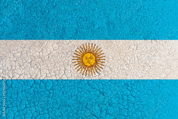Fototapeta Cracked clay lake bed with Argentina flag painted on it (close-up). Concept of climate change, drought and water drying up in Argentina