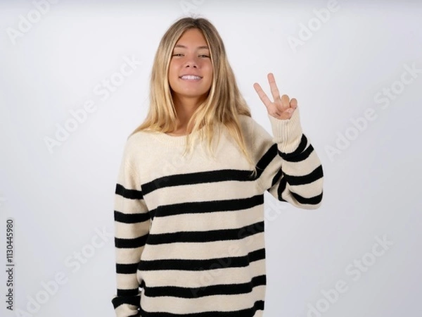 Fototapeta Beautiful teen girl wearing striped sweater showing and pointing up with fingers number two while smiling confident and happy.