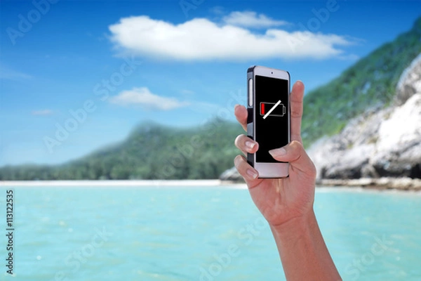 Fototapeta "Battery Low" showing on the smartphone with tropical island background.