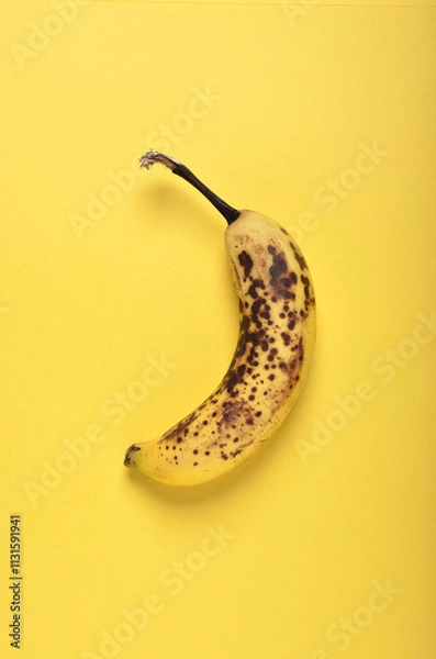 Obraz Single overripe banana top view on yellow background with copy space