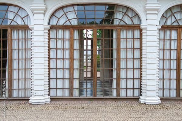 Fototapeta View of the facade of a building with a long corridor-gallery with windows and columns