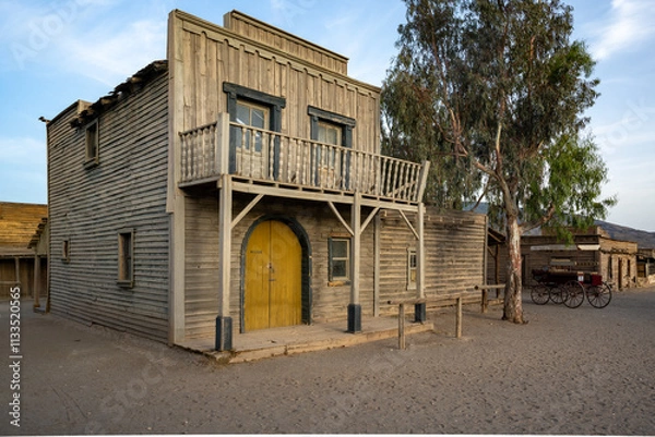 Fototapeta Rustic Western Building with Yellow Door and Balcony, Showcasing Weathered Charm and Historical Heritage in a Cinematic Frontier Setting