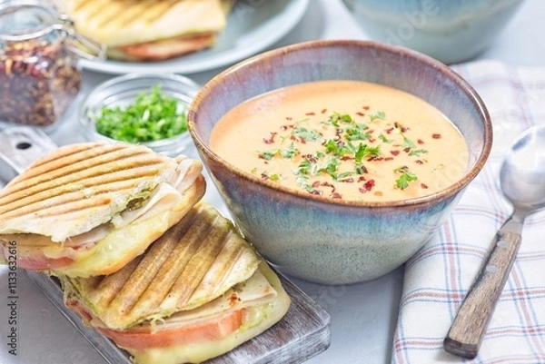 Obraz Red bell pepper cream soup served with grilled turkey panini, horizontal