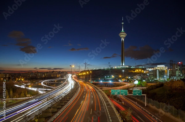 Fototapeta Highways of Tehran Filled with Passing Cars in Front of Milad Tower against Blue Sky with Clouds
