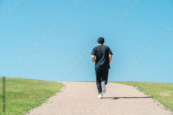 Fototapeta 青空の下でランニング・ジョギングをする男性（アスリート・有酸素運動・ワークアウト・フィットネス）
