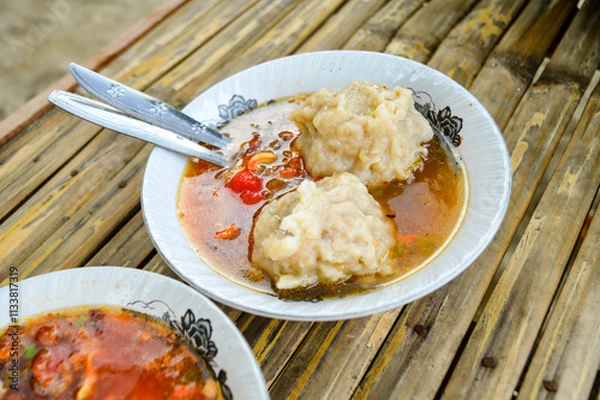 Fototapeta the delicious Two Mie Pentol Bakso or meatball soup in the White bowl with spoon and fork . Two Traditional Food of a Bakso Indonesian .Focus on meatball, Noisy, exposure, similar others