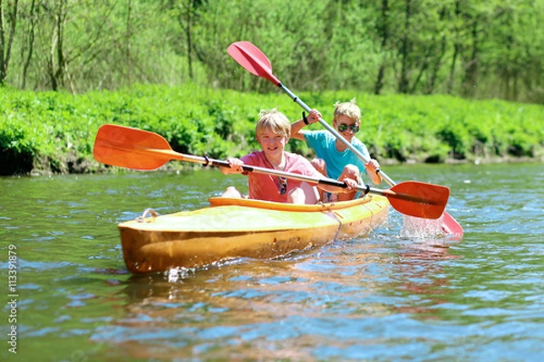 Fototapeta Two boys kayaking on the river. Active happy friends, teenage schoolboys, having fun together enjoying adventurous experience with kayak on a sunny day during summer vacation