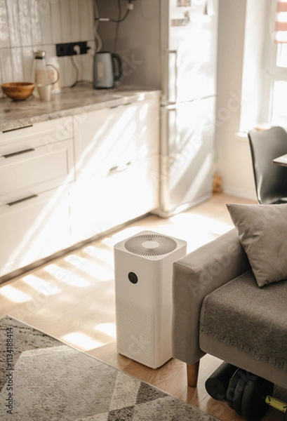 Fototapeta Stylish air purifier from dust and viruses in the interior of the apartment next to the sofa in the kitchen. Health and technology.