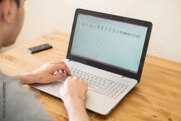 Fototapeta Hands typing on a notebook closeup. Workplace