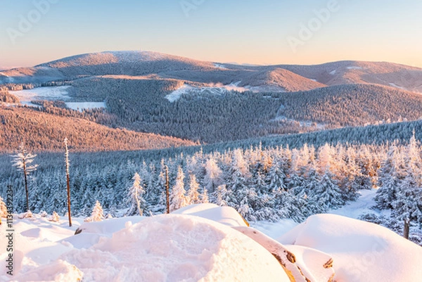 Fototapeta Eastern Sudetes, View of snowy mountain range from hiking trail during winter hike in the mountains, viewpoint of wide winter landscape in the mountains at sunset.