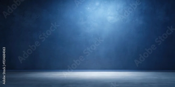 Fototapeta A single spotlight illuminates the center of a textured blue wall, casting a soft glow on the empty concrete floor, creating a minimalist and dramatic backdrop for any composition.