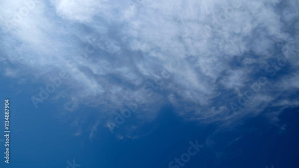 Fototapeta A blue sky with clouds. The clouds are white and fluffy. The sky is clear and bright