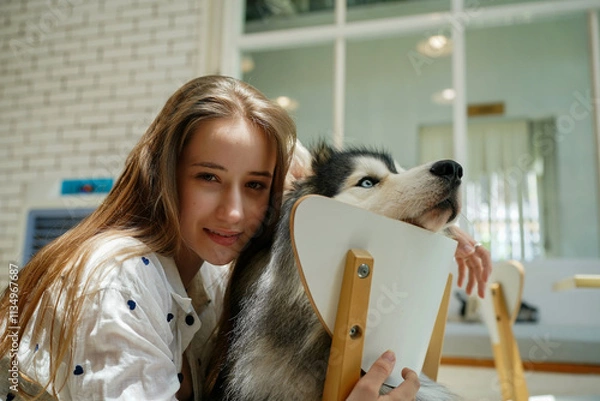 Fototapeta A woman with a dog smiling together in the park, showing happiness and friendship