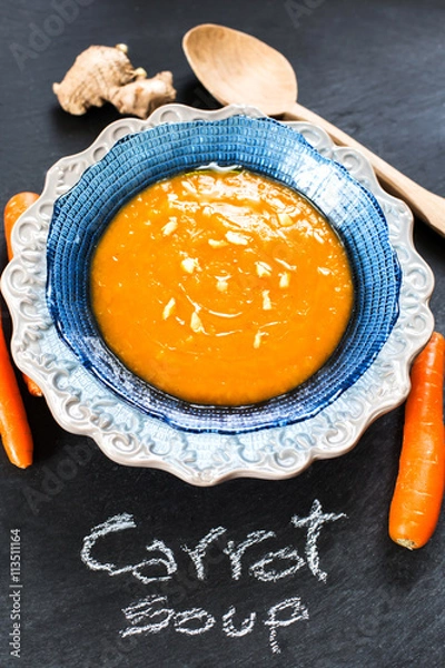 Fototapeta carrot soup flavored with ginger over slate background