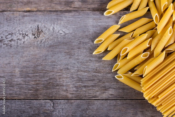 Obraz .macaroni, spaghetti on an old wooden table. Mix of pasta. close up portrait of raw homemade italian pasta, macaroni, spaghetti, and fettuccine.