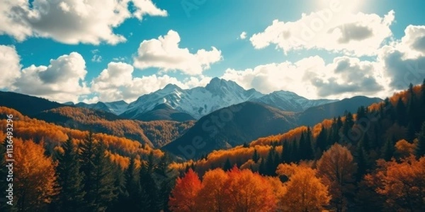Fototapeta Autumnal mountain landscape with vibrant foliage and snow-capped peaks under a partly cloudy sky