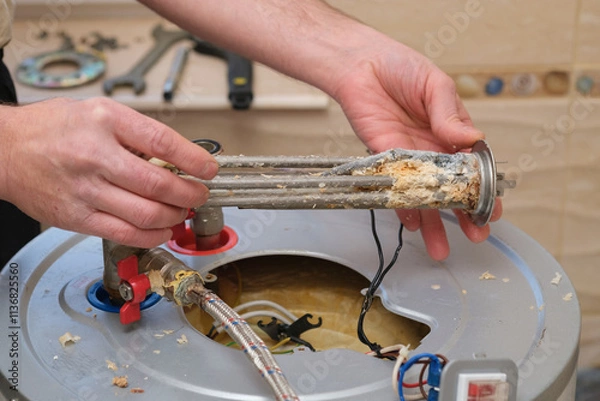 Fototapeta Repairman demonstrates a burnt-out boiler heating element covered with lime coating. Electric Water Heater Maintenance and Repair.
