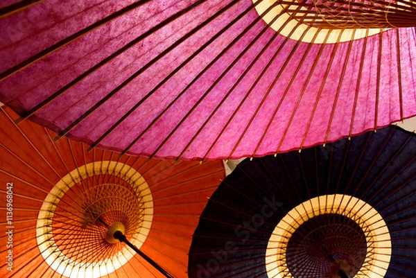 Fototapeta These are colorful Japanese umbrellas made of washi paper. They feature wooden frames and vibrant shades of red, pink, and black, showcasing traditional craftsmanship.