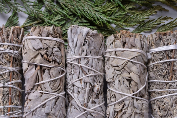 Fototapeta A top view image of several white sage smudge sticks on a cedar bow background.