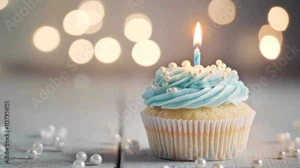 Fototapeta Elegant Blue Cupcake with Lit Candle and Pearl Decorations on Bokeh Background