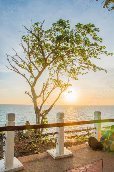 Fototapeta A scenery of a wooden rail with a love keys on a mountain with sea and sunset behind the rail in Chanthaburi Thailand.