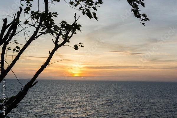 Fototapeta A scenery of sea at sunset with a shadow of tree at the side of photo in Chanthaburi, Thailand.
