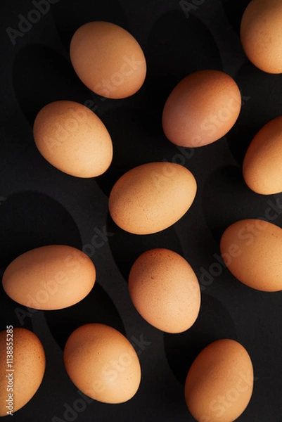 Fototapeta Chicken eggs on black background. View from the top