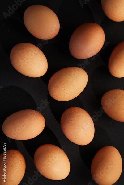 Fototapeta Chicken eggs on black background. View from the top