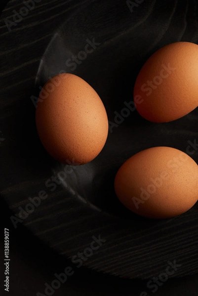 Fototapeta Chicken eggs on black background. View from the top