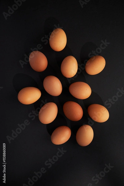 Fototapeta Chicken eggs on black background. View from the top