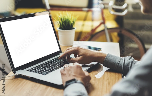 Obraz Close-up of young professional businessman sitting at office and using laptop with blank screen with space for your design, mock-up of template computer, hipster man working at cafe on device