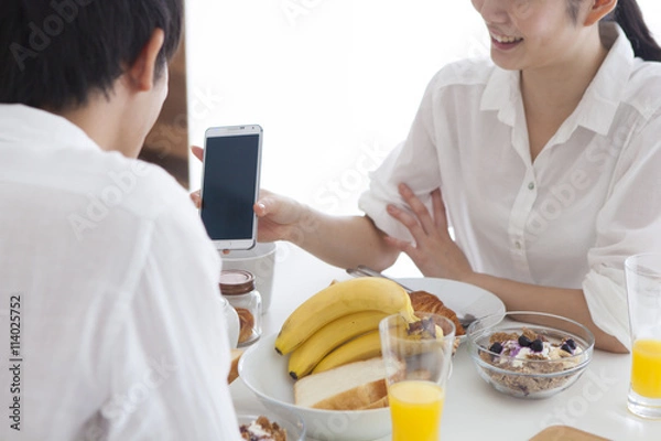 Fototapeta Woman is showing a smartphone to men at the table