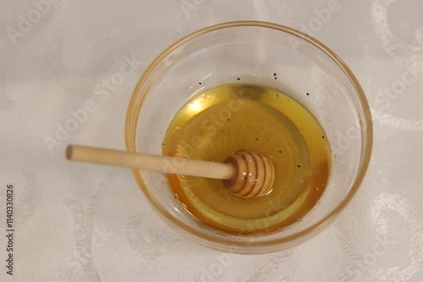Fototapeta Honey bee in a bowl of honey.A bowl with honey and a dipper to take honey
